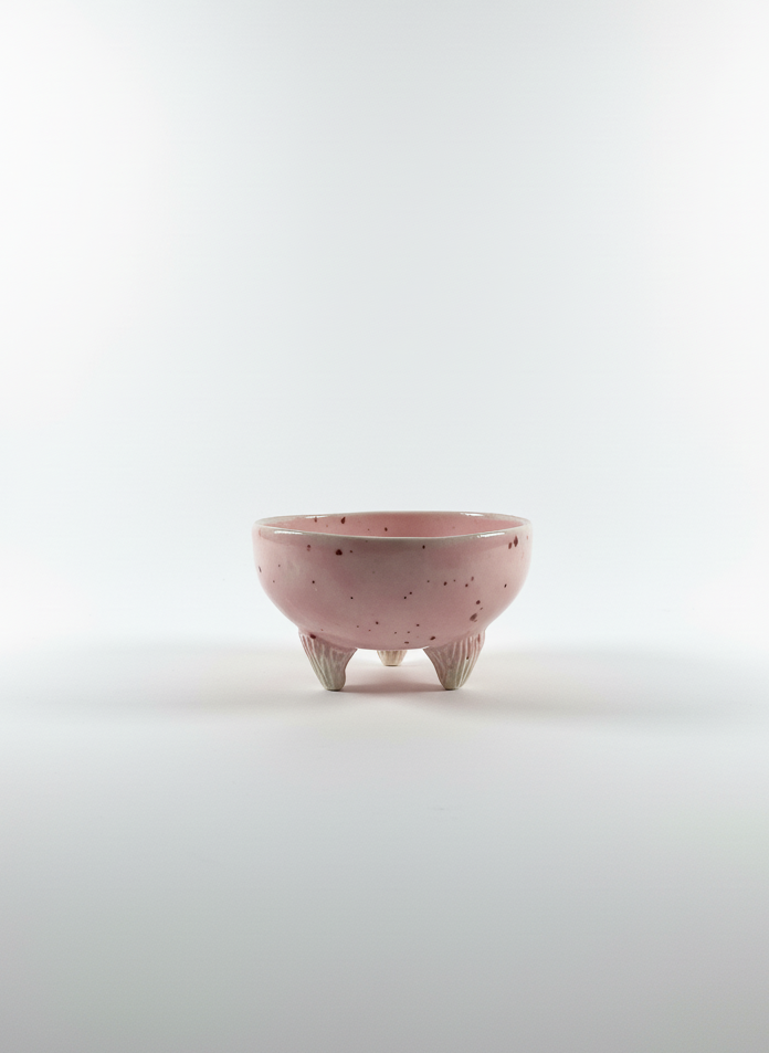 Pink ceramic bowl with three legs on a white background