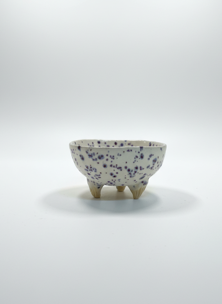 Small ceramic bowl with blue speckles on a white background
