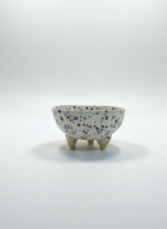 Small ceramic bowl with blue speckles on a white background