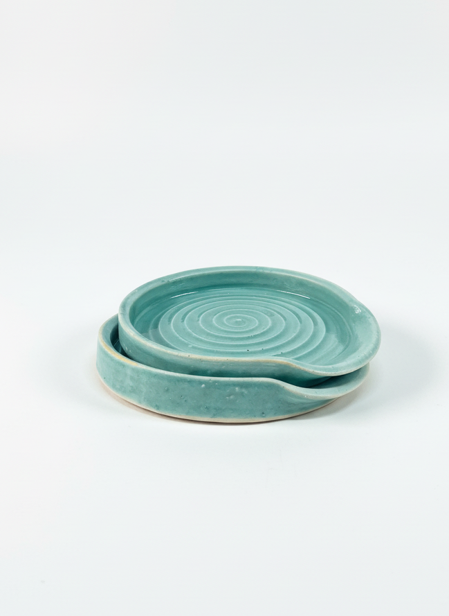 Two turquoise ceramic plates stacked on a white background