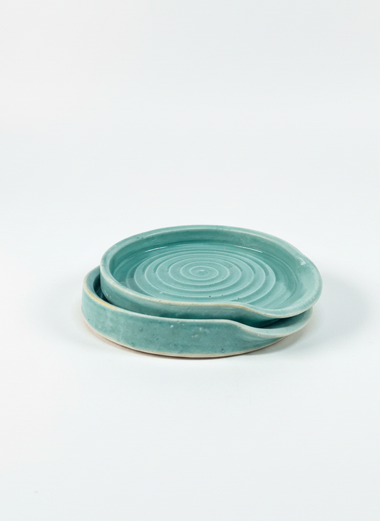 Two turquoise ceramic plates stacked on a white background