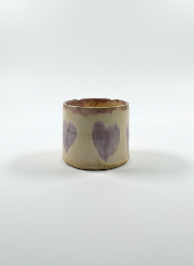 Ceramic cup with purple heart designs on a white background