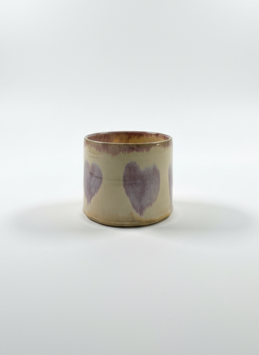 Ceramic cup with purple heart designs on a white background
